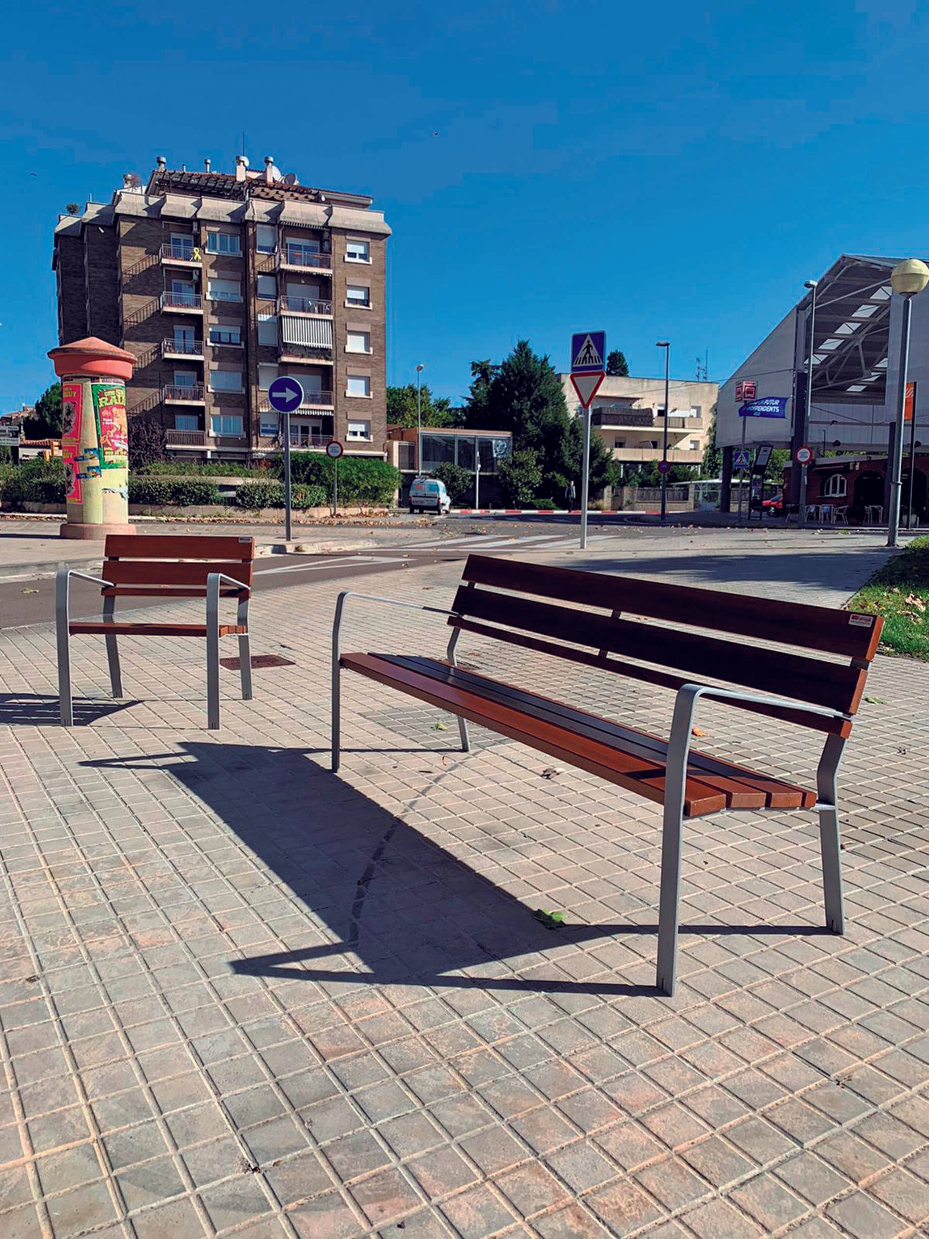 Parkbank Emma Standard mit Parkstuhl in einer Stadt mit einem großen Haus im Hintergrund