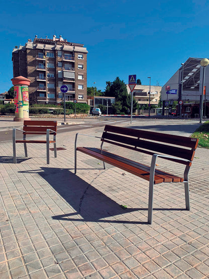 Parkbank Emma Standard mit Parkstuhl in einer Stadt mit einem großen Haus im Hintergrund