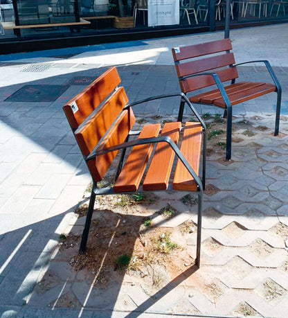 Zwei schlichte Stühle aus braunem Holz mit grauen Metallgestell auf Steinplatten
