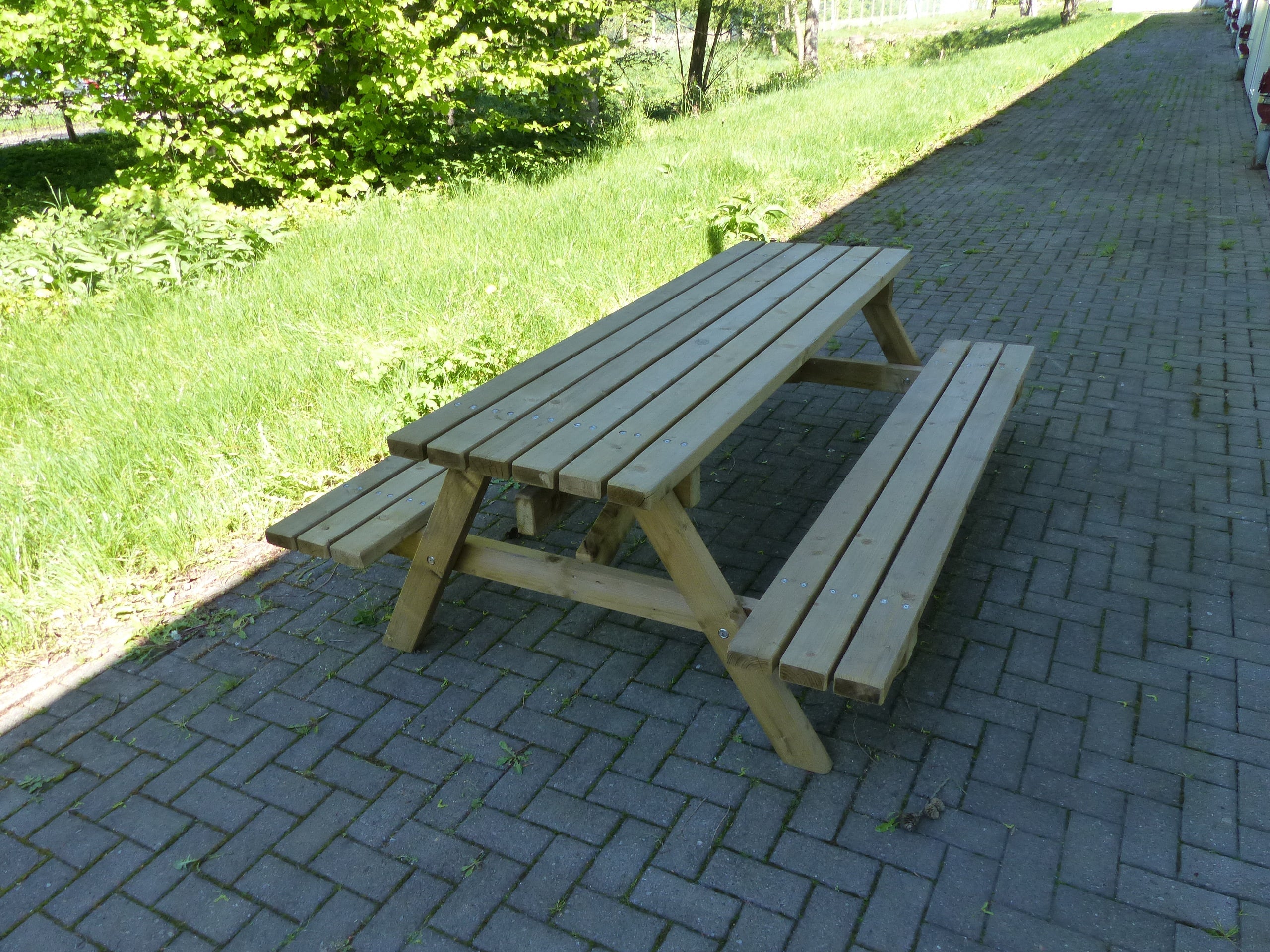 Moderne Bank-Tisch-Kombination aus Holz für den Park und Schulhof auf Pflasterstein